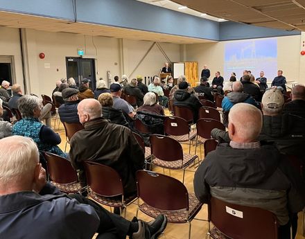 a hotel room filled with people sitting in chairs in a meeting