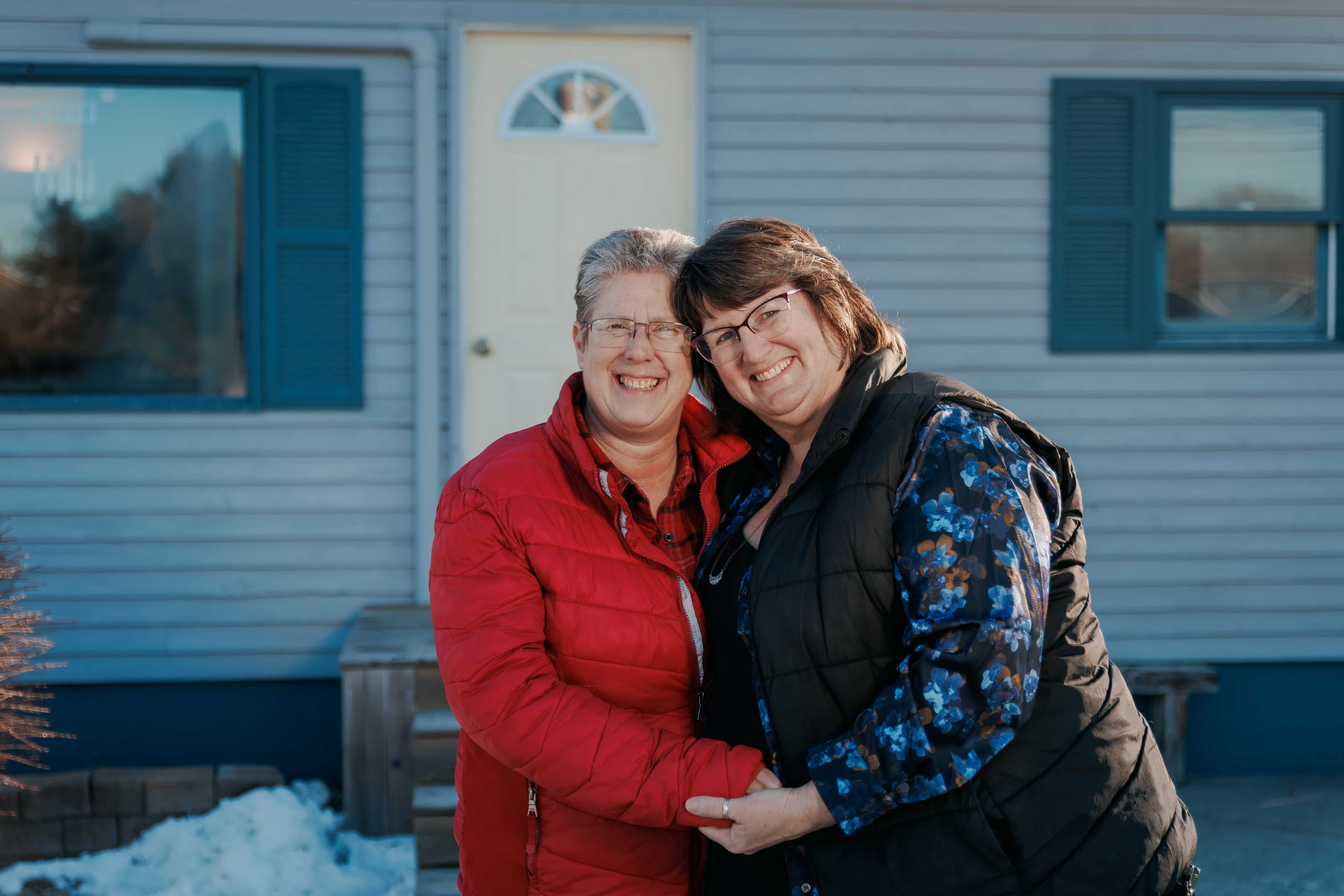 Two people hugging each other in front of a house